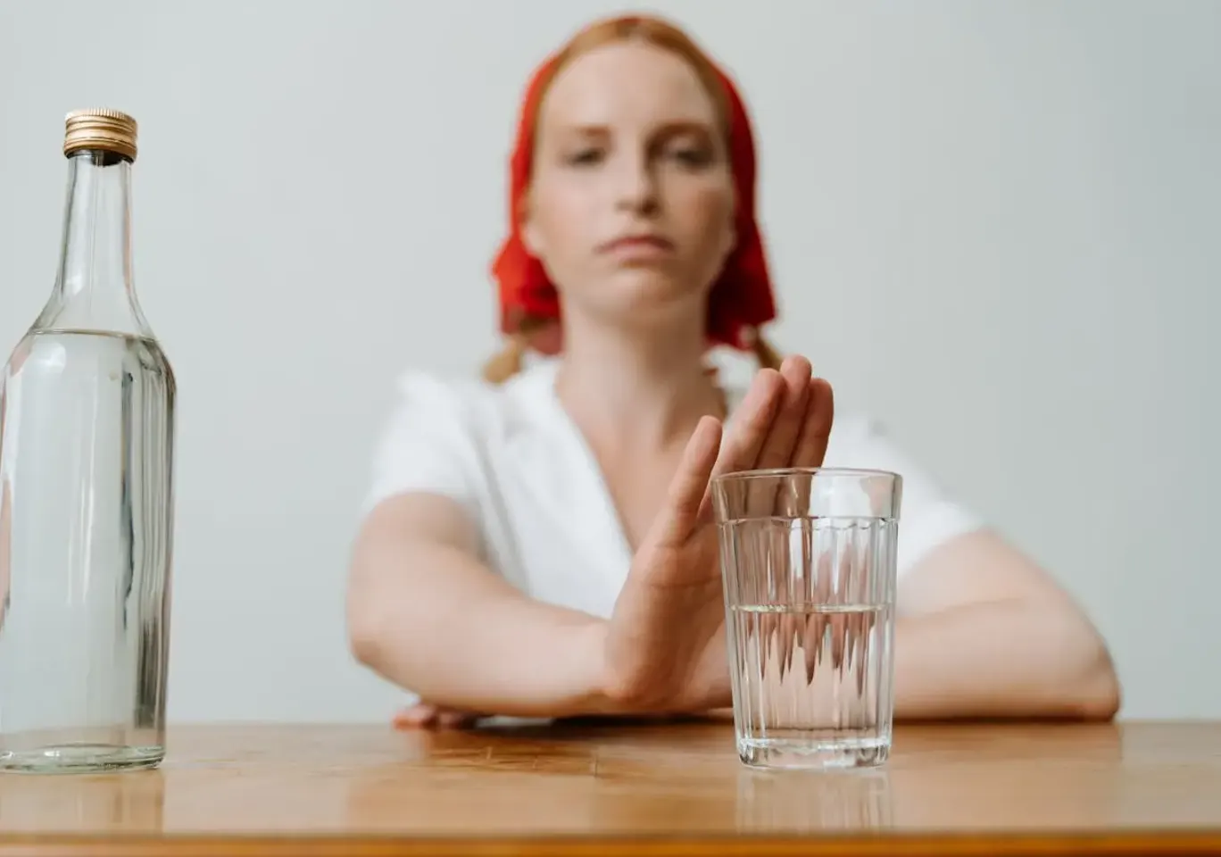Leczenie alkoholizmu Kalisz: kobieta odsuwa butelkę i sięga po wodę